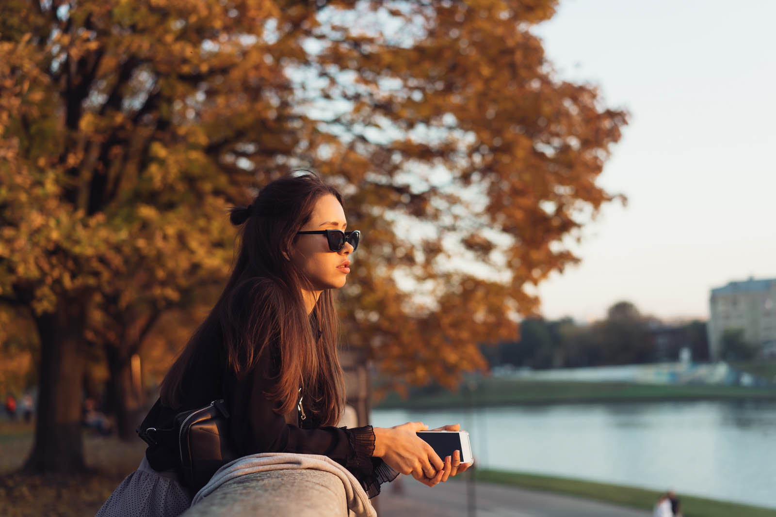 Attractive woman using smartphone outdoors and looks into the distance
